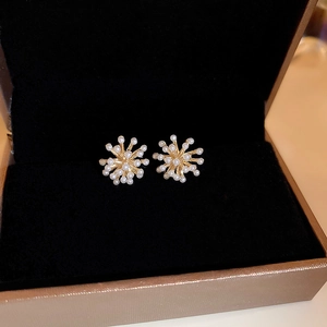 Détail macro de boucles d'oreilles feux d'artifice en perles dorées dans un écrin noir