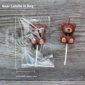Vista detallada de velas de pastel de oso pardo con soportes blancos sobre madera