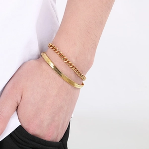 Detail of layered gold cuban and snake chain bracelets worn on a wrist for a chic look