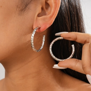Detailed view of silver hoop earrings with a textured geometric diamond-cut pattern