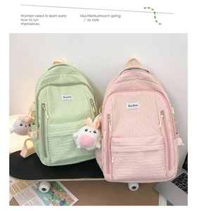 Détail des sacs à dos à bulles rose et vert avec pendentifs lapin posés sur un skateboard