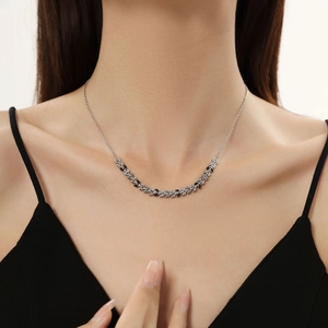 Detail view of titanium steel necklace with black and silver leaf motifs worn by model