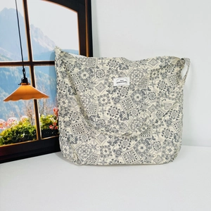 Detail of floral canvas tote bag featuring beige paisley pattern and woven front label