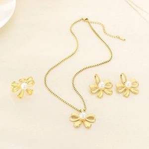 Flat lay of elegant gold bow jewelry set with pearls on beige textured background