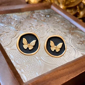 Detailed macro shot of vintage gold butterfly studs on embossed glass display