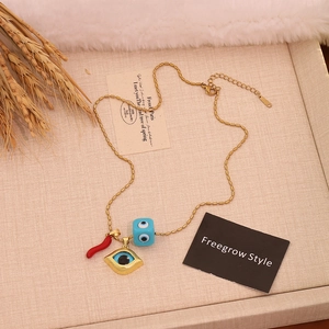 Bohemian gold beaded necklace with red chili, evil eye pendants on a textured tray
