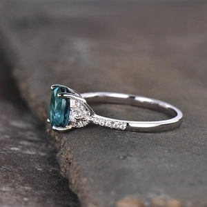 Macro zijaanzicht van een ring met ovale groenblauwe edelsteen en zijdiamanten