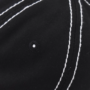 Macro detail of black washed cotton baseball cap with white contrast stitching and eyelet