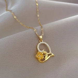 Detail of gold heart pendant necklace with floral inlay and pavé crystals on silk fabric