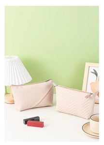 Beige dumpling-shaped cosmetic bags with pleated texture and wavy quilting in a lifestyle setting