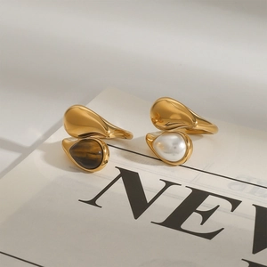 Eleganti anelli a goccia d'oro con occhio di tigre e perla su una rivista di moda