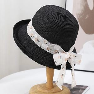 Elegante cappello di paglia nero con nastro a fiori su supporto di legno