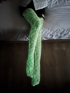 Gros plan sur des bas résille vert néon lumineux à motif de toile d'araignée pour Halloween