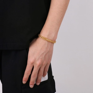 Detailed view of a gold-plated stainless steel curb chain bracelet on a male wrist