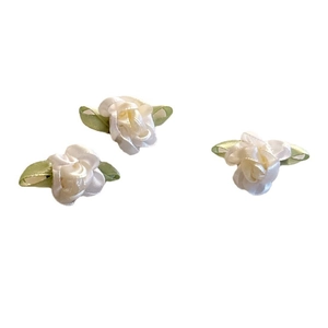 Trois fleurs en ruban de satin ivoire avec feuilles vertes sur fond blanc pur