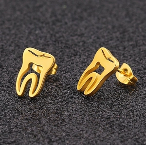 Macro detail of gold-plated tooth-shaped stud earrings with smooth metallic finish