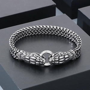 Detail of silver steel woven bracelet featuring dual dragon heads and circular clasp