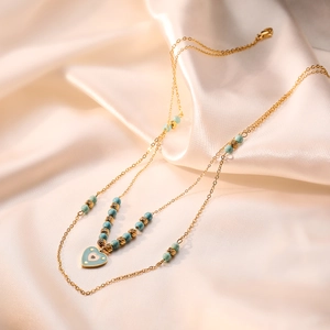 Bohemian gold heart pendant necklace with turquoise beads on champagne silk background