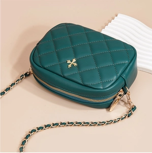 Detail of dark green quilted crossbody bag with gold cross hardware and chain strap