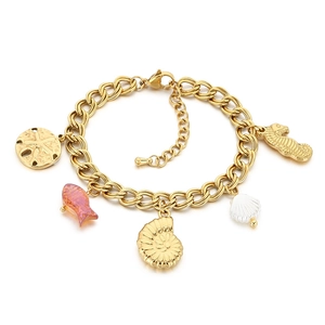 Bracelet à breloques océan doré avec poisson rose, étoile de mer et coquillages sur fond blanc