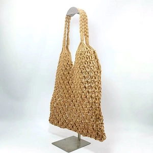 Detail of beige hand-woven tote bag with hollow mesh pattern and sturdy handles
