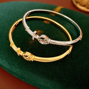 Detail of gold and silver cross bangles with pave crystals on green velvet stand