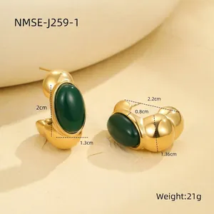 Macro detail of vintage gold C-shaped earrings with emerald green oval gemstones