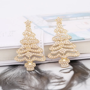 Exquisite gold hollow Christmas tree earrings with white pearls on a white notebook