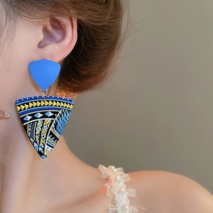 Macro detail of large geometric bohemian painted drop earrings worn by a model