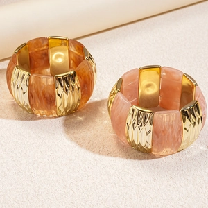 Detailed view of wide acrylic and gold metal elastic bracelets with amber and pink textures