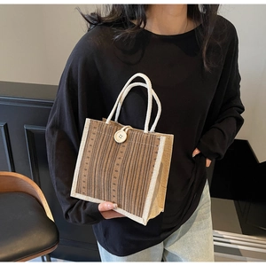 Detailed texture of striped linen handbag with white rope handles and decorative button