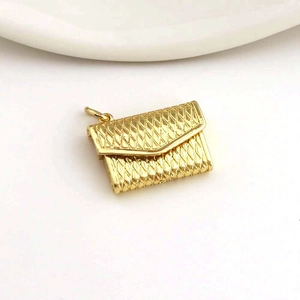 Macro detail of a mini gold-tone envelope bag pendant with textured quilted pattern
