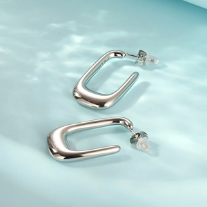 Macro detail of polished silver U-shape earrings showing the smooth mirror finish surface