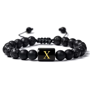 Détail du bracelet ajustable en pierre de lave avec cylindre doré et lettre X