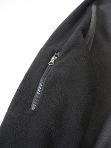 Close-up of black polar fleece fabric with silver metal zipper pocket and sharp texture