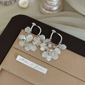 Silver geometric petal tassel hoop earrings with vintage shell texture on silk background