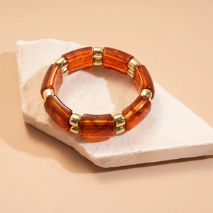 Detail of vintage amber resin square beads and gold metal spacers on stone base