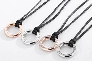 Detail of round titanium steel pendants in rose gold and silver on black cords
