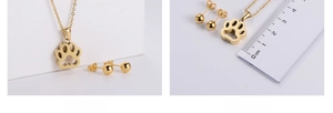 Detailed view of gold plated hollow paw print necklace and stud earrings set with ruler