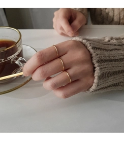Close-up of three minimalist 925 sterling silver thin gold rings worn on a hand