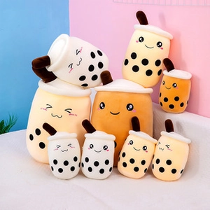 Detail of soft plush bubble tea cups in beige and brown colors on white surface