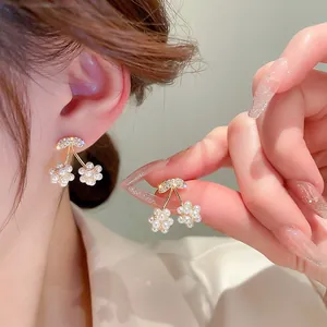 Detail of cherry stud earring with white pearls and sparkling crystal leaves on ear