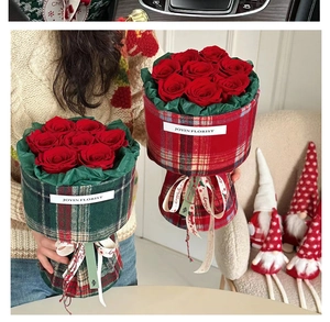 Red rose bouquet wrapped in red and green tartan fabric with holiday ribbons