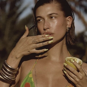 Golden stretch wide bracelet and chunky hoop earrings on model with green swimwear