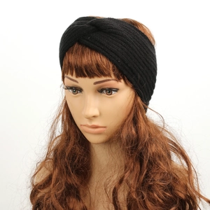 Detail view of a black knitted winter headband on a model head for warm ear protection