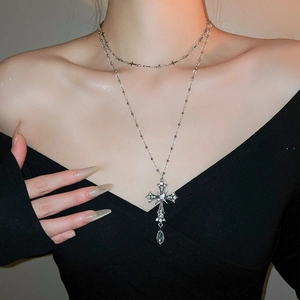 Detail of gothic silver-toned double layer necklace with crystal cross and teardrop charms