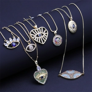 Golden heart-shaped evil eye pendant necklaces set with zircon stones on dark background