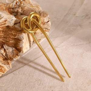 Close-up of a 18k gold-plated pretzel knot hair pin on a natural stone background