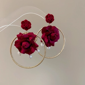 Detail view of wine red fabric rose earrings with gold hoop and small white pearls