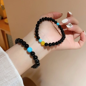Detail of beaded bracelets featuring black agate beads with blue and yellow accents